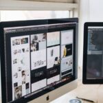 Modern office desk setup with dual monitors displaying design software, ideal for tech and business themes.